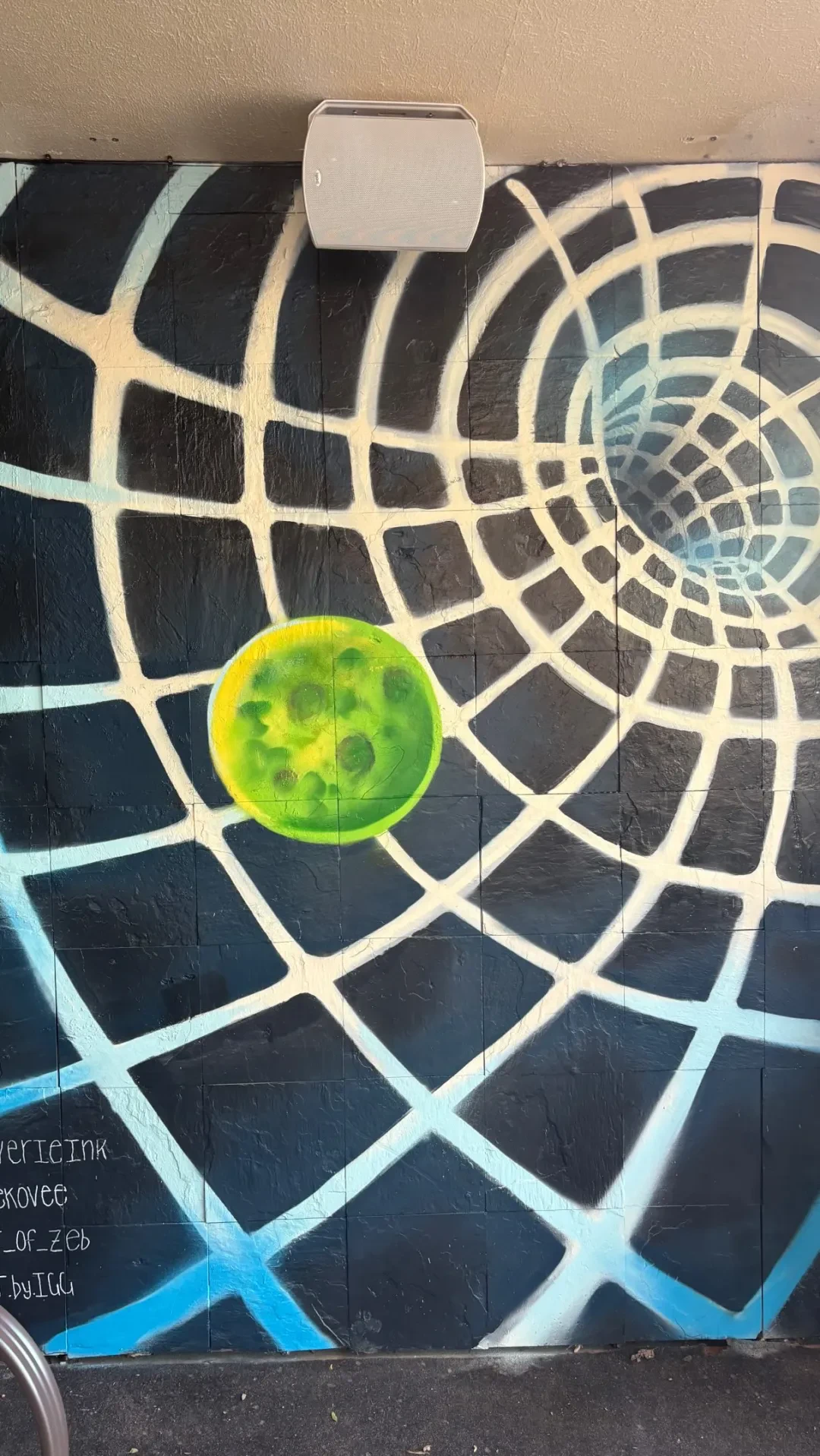 A mural inside the venue: a spiderweb in blue and white spray paint with a bright green moon.